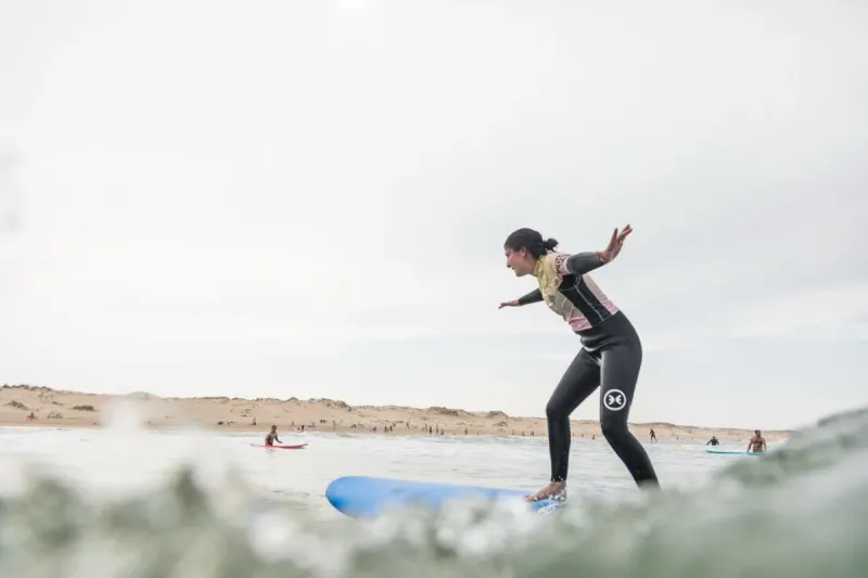 Élève de surf sur la planche avec moniteur