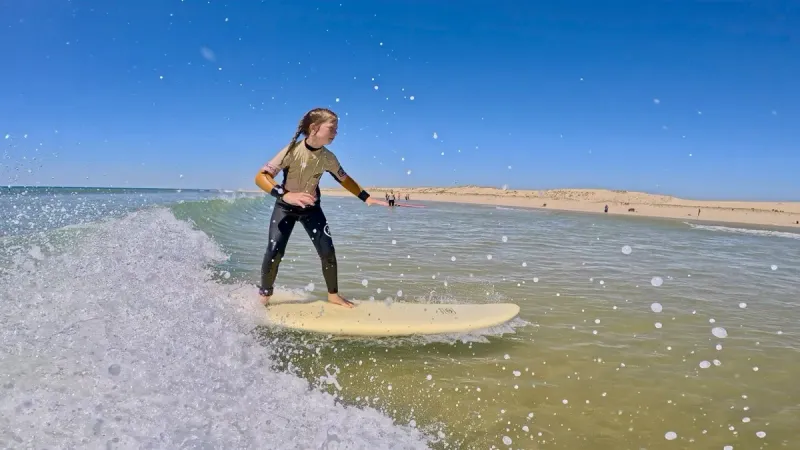 Jeune surfeuse devant les dunes
